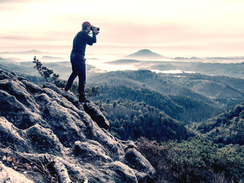 Man photographing on mountain against sky