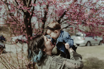 Mother and daughter against tree