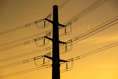 Low angle view of silhouette electricity pylon against sky during sunset