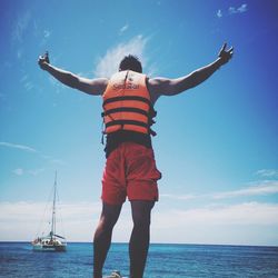 Rear view of person standing in sea against sky