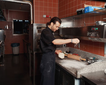 Pizza making process. male chef hands making authentic pizza in the pizzeria kitchen.