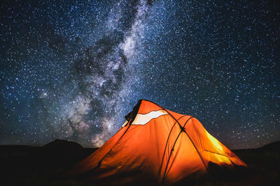 Tent on field against starry sky at night