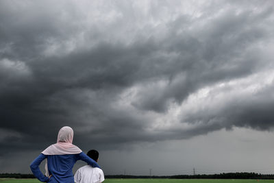 Rear view of couple sitting against sky