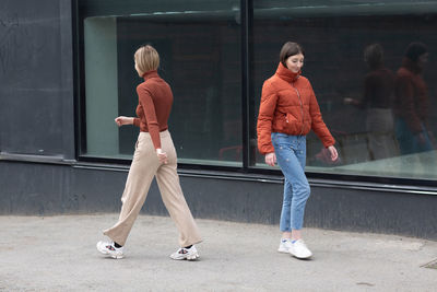 Full length of friends standing on glass in city