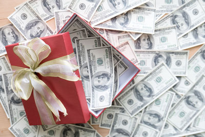 High angle view of gift box with paper currencies on table