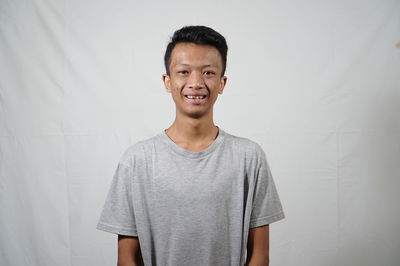 Portrait of smiling man standing against curtain