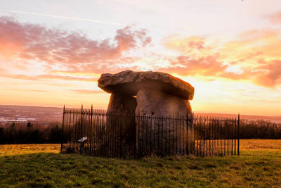 Built structure on field against sky during sunset