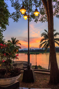 Street light by lake against sky during sunset