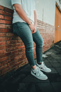 Low section of woman standing against brick wall