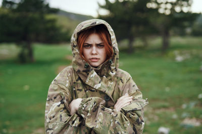 Portrait of young woman standing against trees