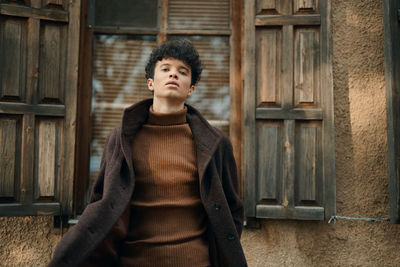 Young woman standing against wall