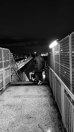 Rear view of man on illuminated railing at night