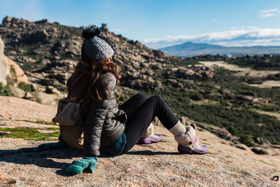 Midsection of woman sitting on rock against sky