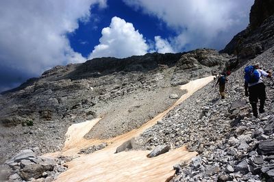 People on rocky mountain against sky