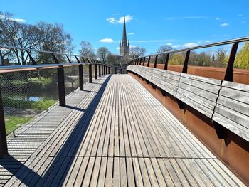 Footbridge over footpath amidst buildings against sky