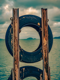 Close-up of tyre with sea behind against sky