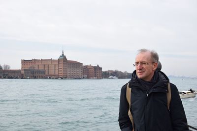 Portrait of man standing by river against sky
