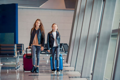 Sisters with suitcases walking in airport