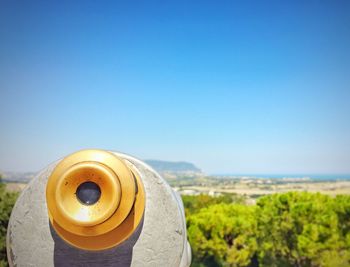 Close-up of coin-operated binoculars by sea against clear blue sky