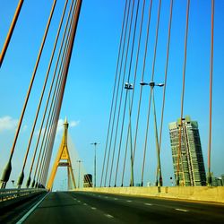 Low angle view of suspension bridge against clear blue sky