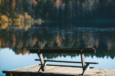 Empty bench on pier by lake