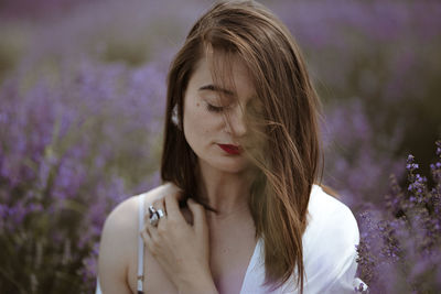 Young woman with purple flower in field