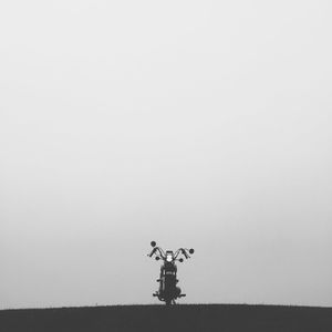 Motorcycle parked on hill against sky
