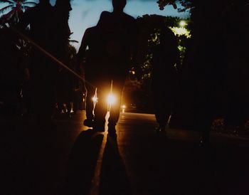 Silhouette people walking on illuminated street at night