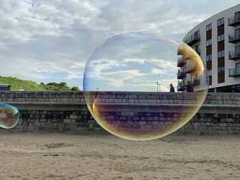 Digital composite image of bubbles and building against sky