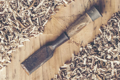 Directly above shot of chisel and wood shavings on table