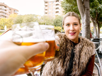 Profile of a young woman toasting with a glass of beer , sitting on an outdoor terrace