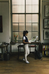 Side view of woman sitting on chair at home