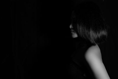 Close-up of woman standing against black background