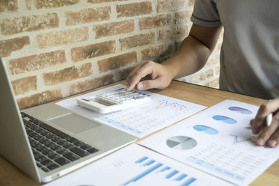 Midsection of businessman using laptop at desk in office