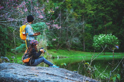 Side view of man sitting on land in forest