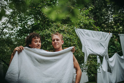 Couple with towel standing against trees