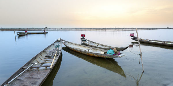 Boat moored in lake against sky during sunset