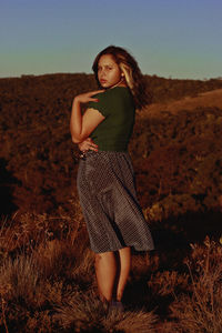 Young woman standing on field against clear sky