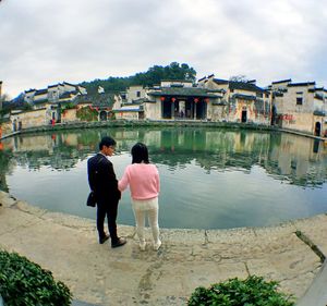 Rear view of people standing at lakeshore