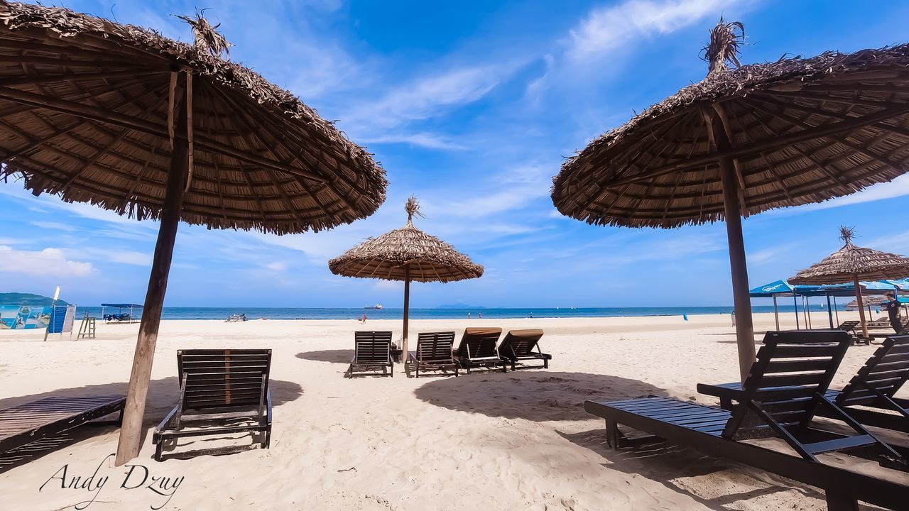 PANORAMIC VIEW OF LOUNGE CHAIRS AND PARASOLS ON BEACH