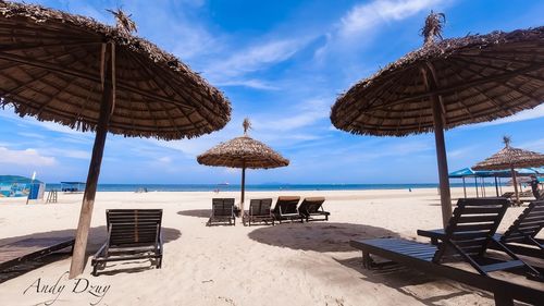 Lounge chairs and parasols on beach against sky