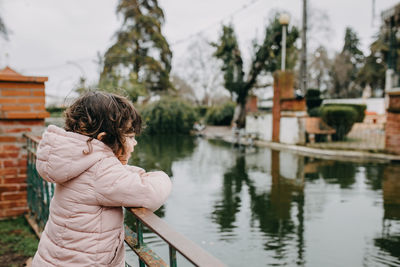 Rear view of woman standing by lake