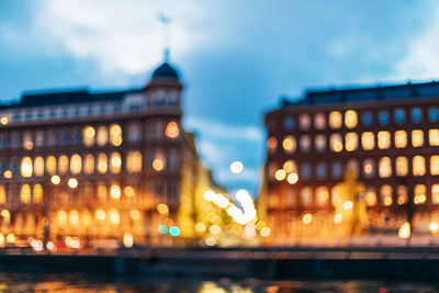 Illuminated buildings against cloudy sky