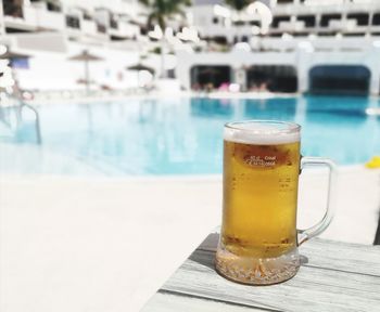 Close-up of beer glass on table by swimming pool