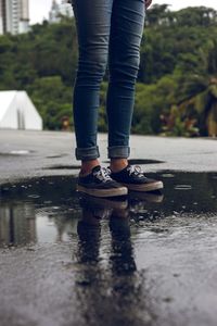 Low section of woman standing in puddle