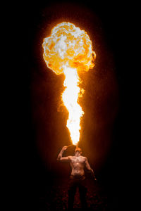 Man exhaling fire against black background