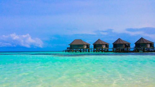 Houses by swimming pool by sea against blue sky