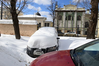 Snow covered street by buildings in city