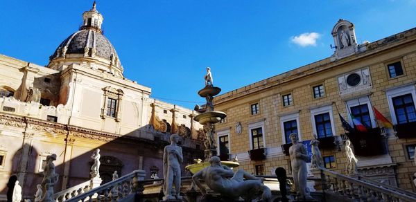 Low angle view of statue against buildings in city