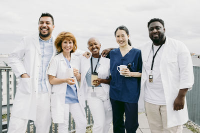 Portrait of smiling multiracial medical staff against sky